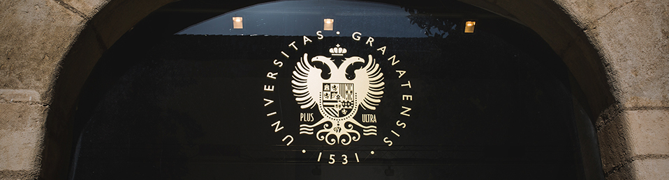 Detalle puerta de cristal en Patio del Hospital Real con escudo UGR en vinilo dorado en la parte superior